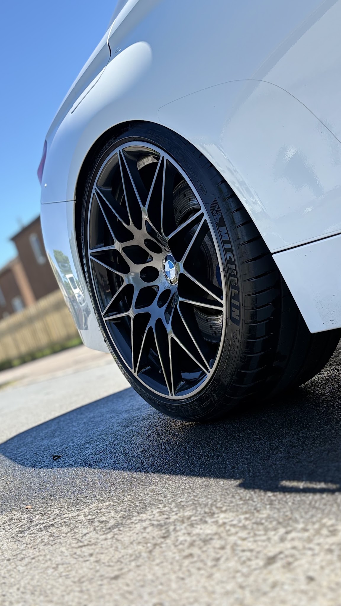 A cleaned black alloy wheel and dressed tyre on a white BMW