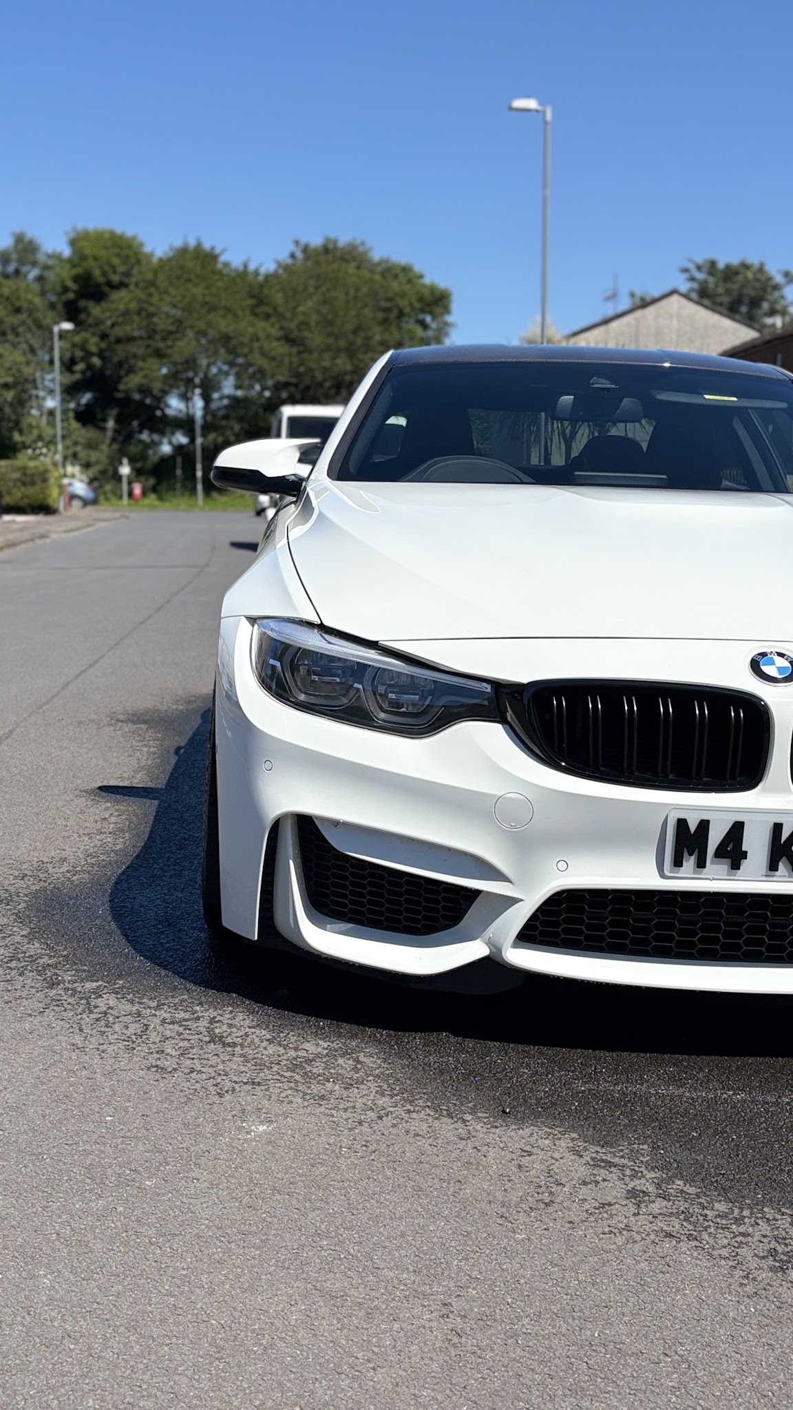 A close front view of a white BMW M4 after detailing